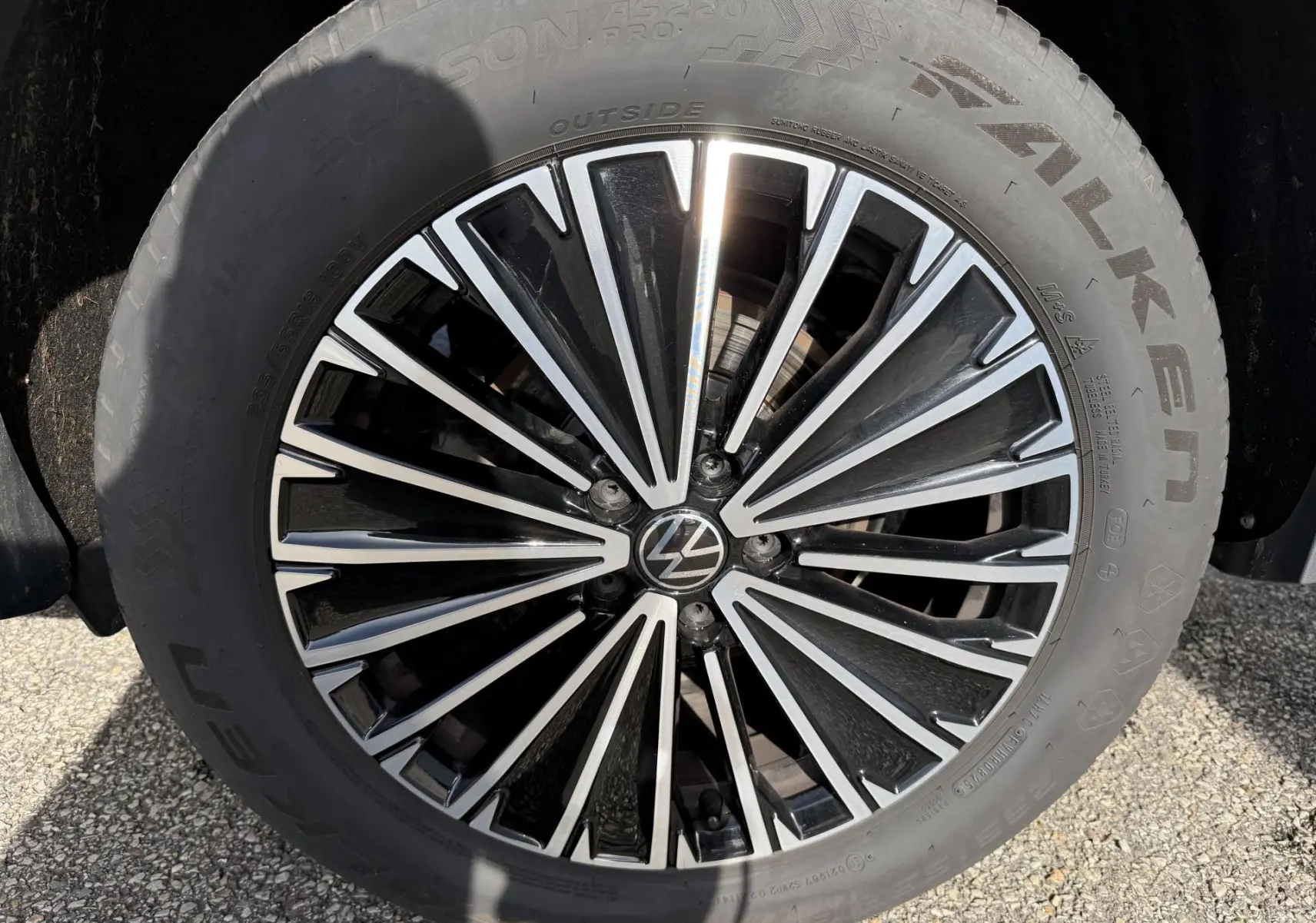 Gros plan sur la jante alliage noir et argent de 18 pouces du Volkswagen Tiguan blanc, avec logo VW central.