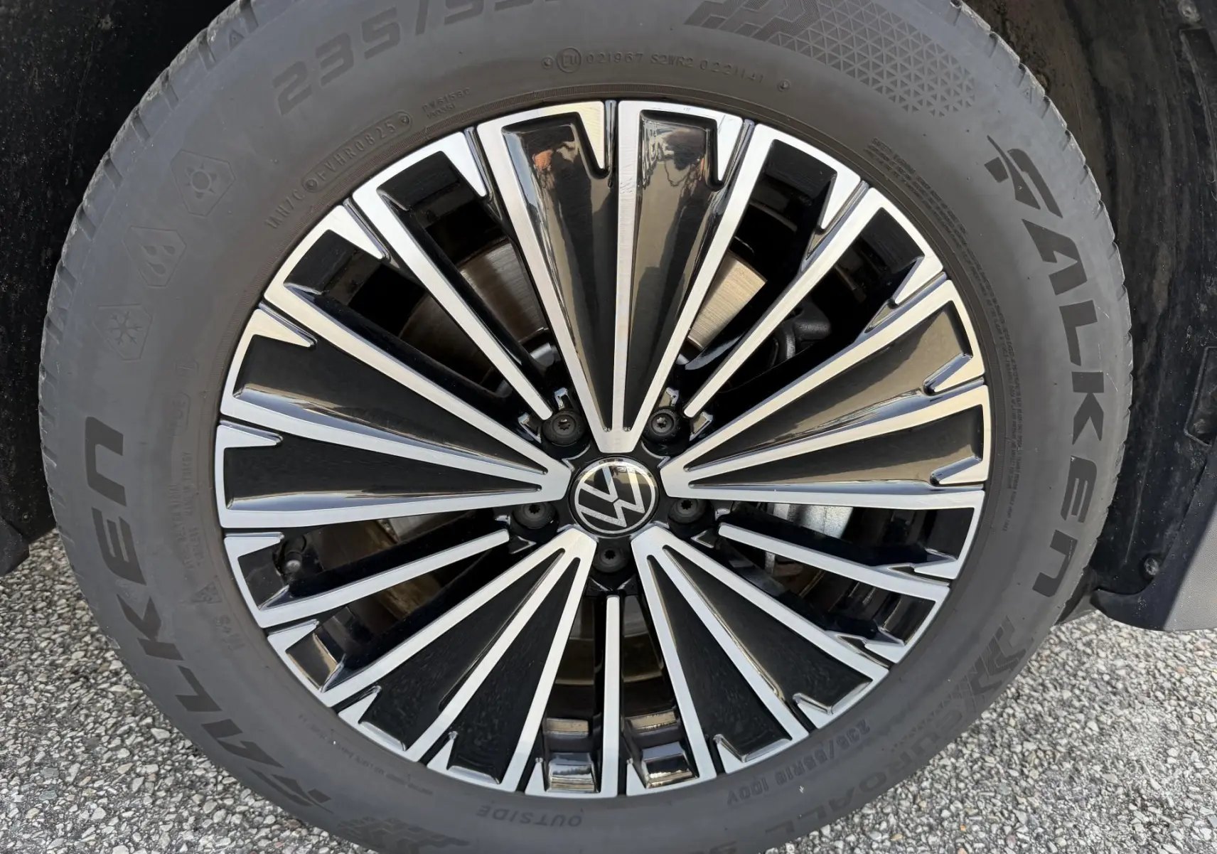 Gros plan sur la jante alliage noir brillant Napoli 18 pouces du Volkswagen Tiguan blanc, avec pneu Falken visible.