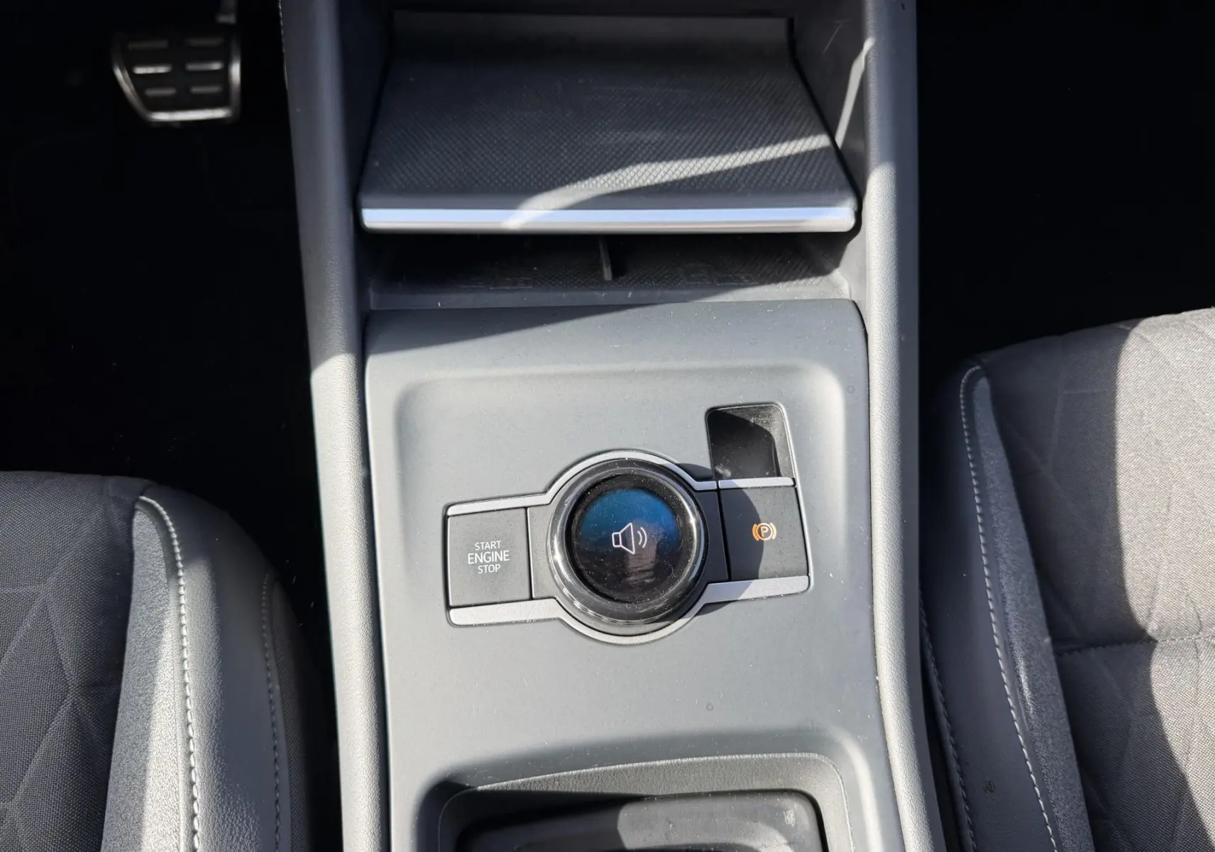 Vue plongeante sur la console centrale grise du Volkswagen Tiguan 2025, avec bouton Start/Stop et commande sonore.