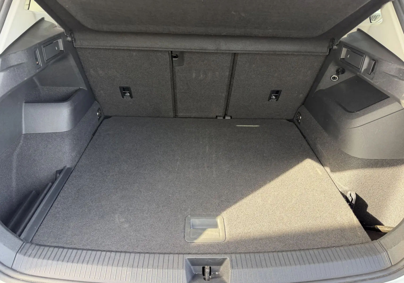 Coffre ouvert du Volkswagen Tiguan blanc, vue intérieure montrant un espace de chargement propre et bien agencé.