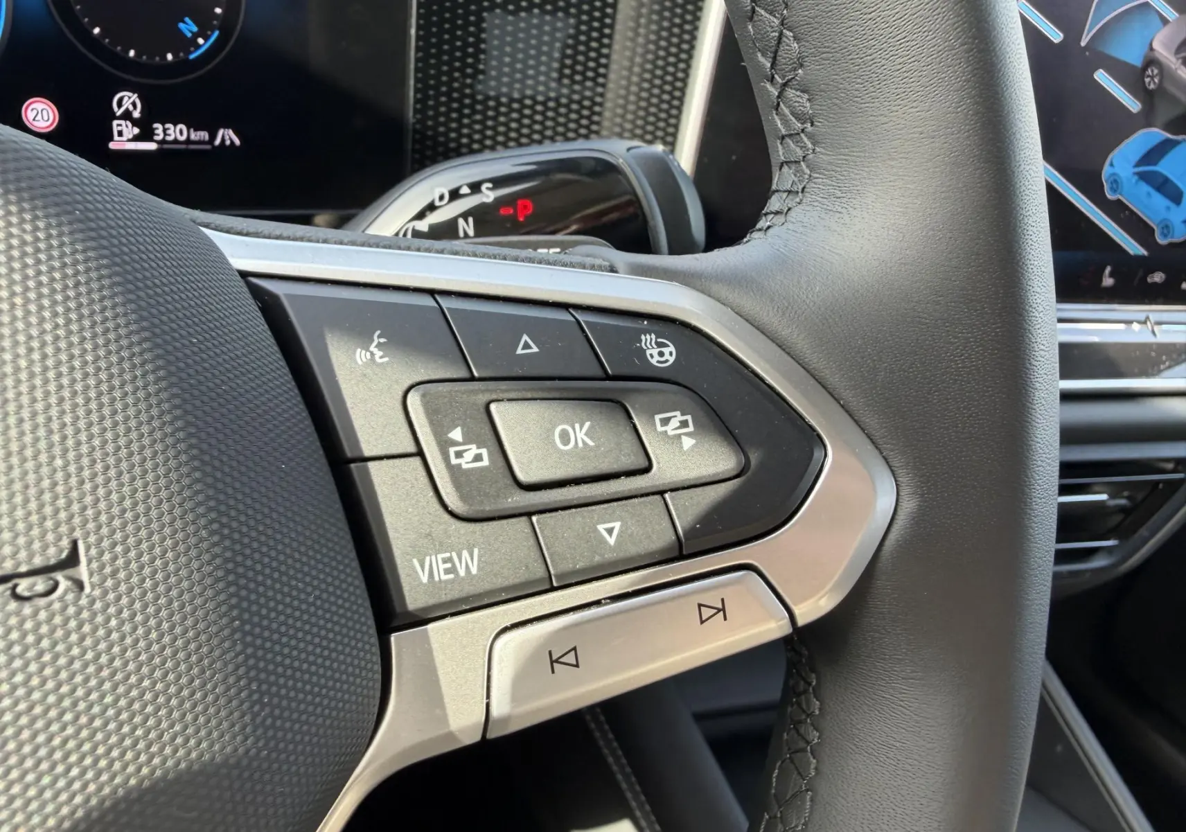 Gros plan sur le volant multifonction en cuir noir du Volkswagen Tiguan 2025, avec commandes intégrées et affichage digital en arrière-plan.