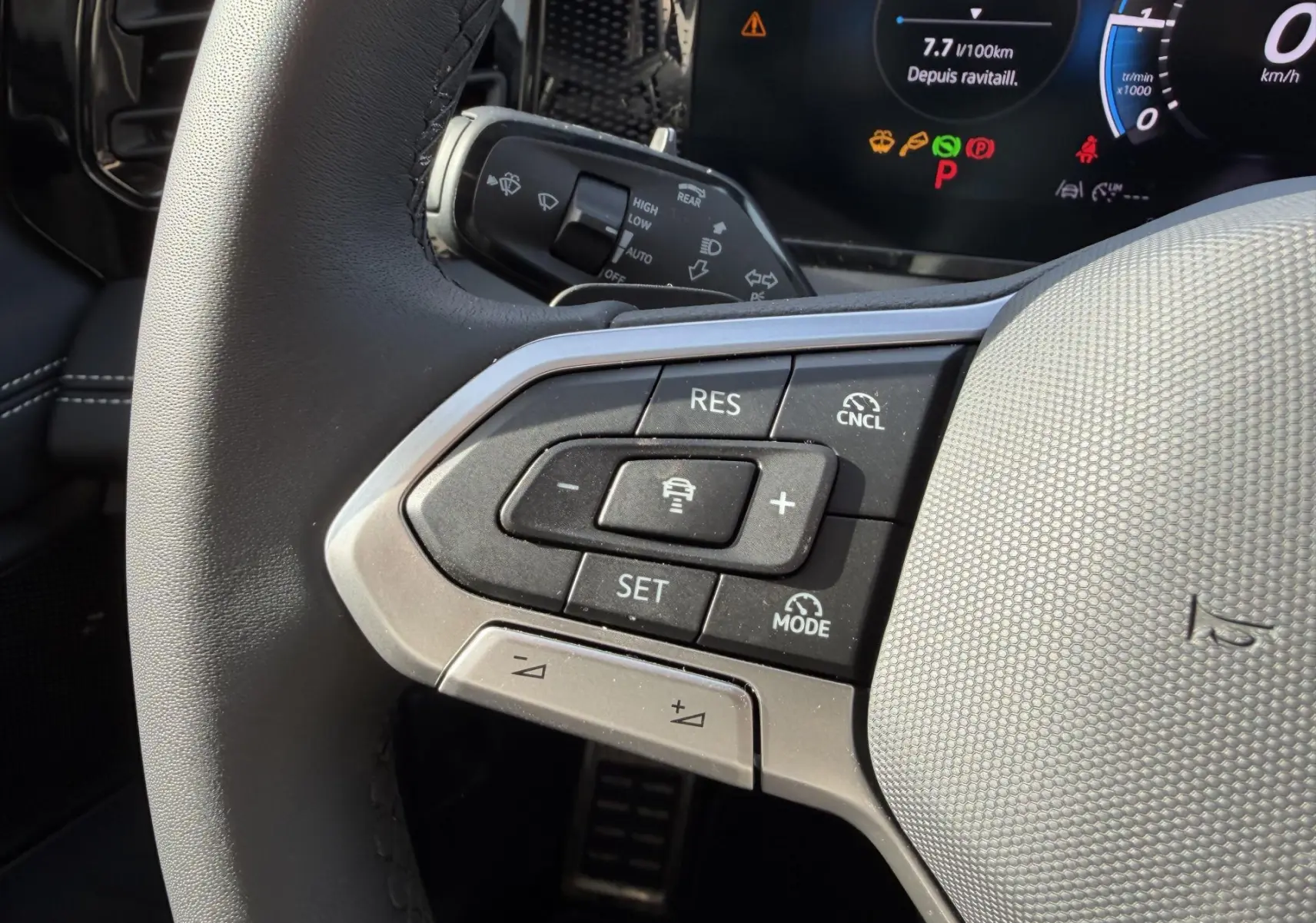 Gros plan sur le volant multifonction cuir noir du Volkswagen Tiguan 2025, avec commandes de régulateur adaptatif visibles.