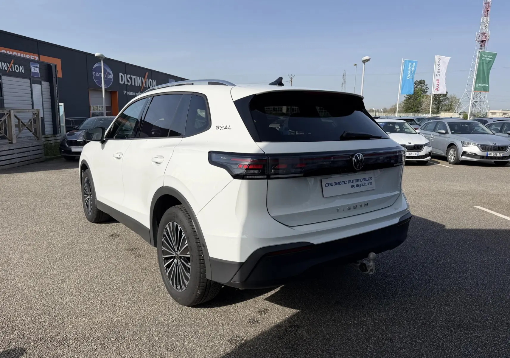 Vue 3/4 arrière droite d’un Volkswagen Tiguan blanc avec attelage rabattable et jantes alliage noires brillantes.