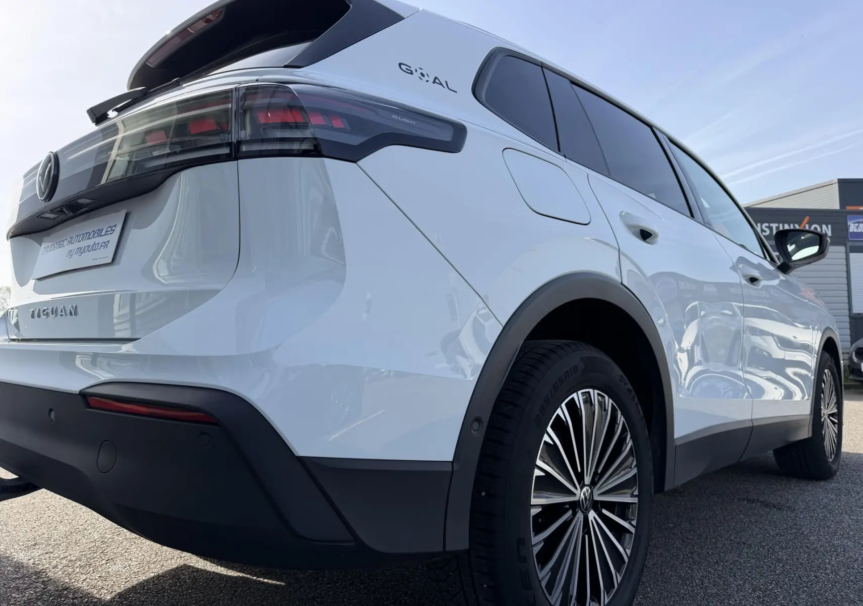 Vue 3/4 arrière droite du Volkswagen Tiguan blanc avec jantes alliage noir brillant et feux arrière LED sombres.