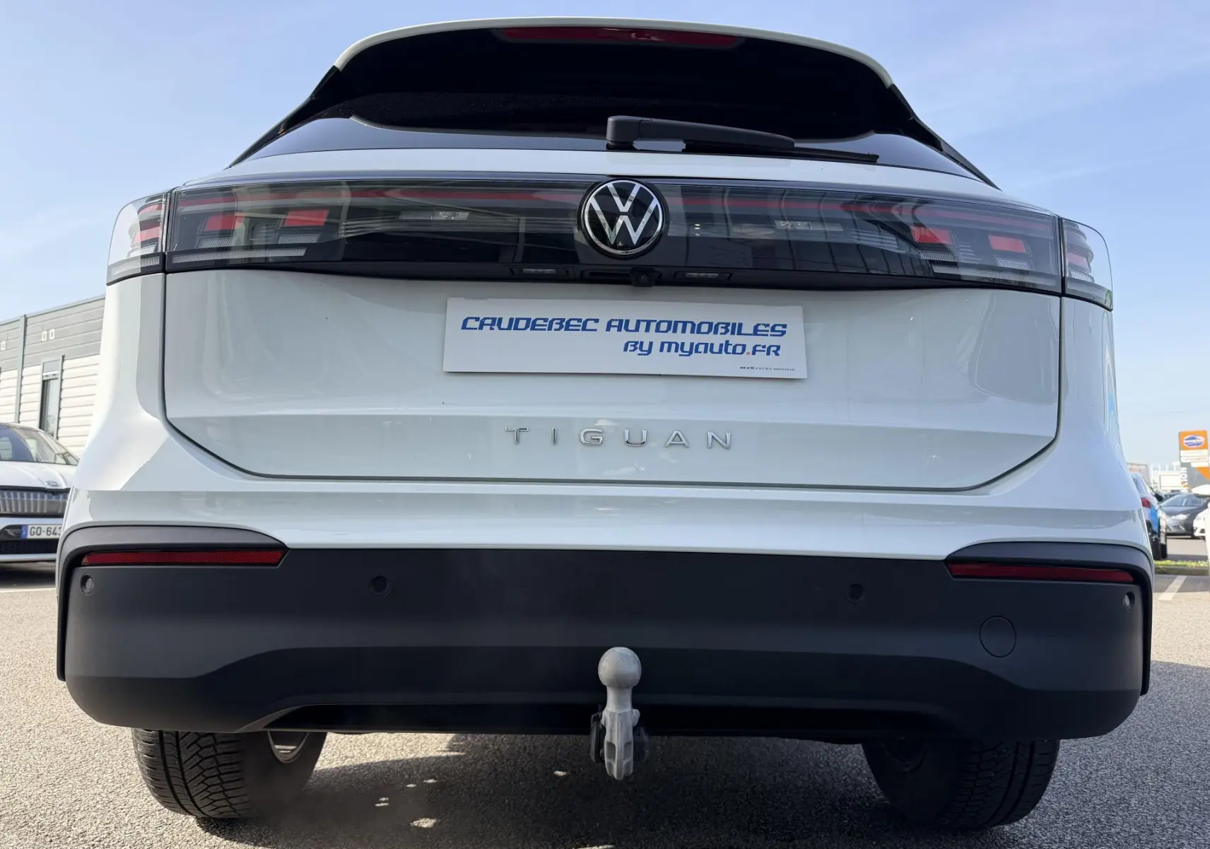 Vue arrière du Volkswagen Tiguan blanc 2025 avec attelage rabattable et feux arrière LED noirs.