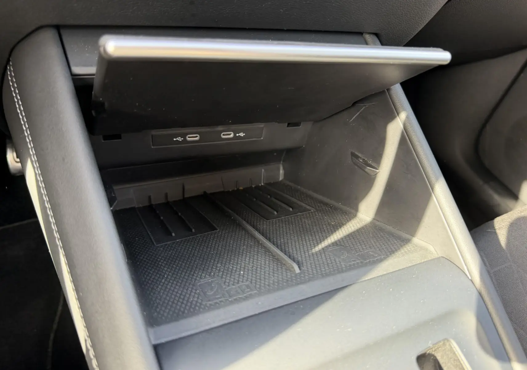 Gros plan sur la console centrale ouverte du Volkswagen Tiguan 2025, montrant les ports USB et l'espace de rangement noir.