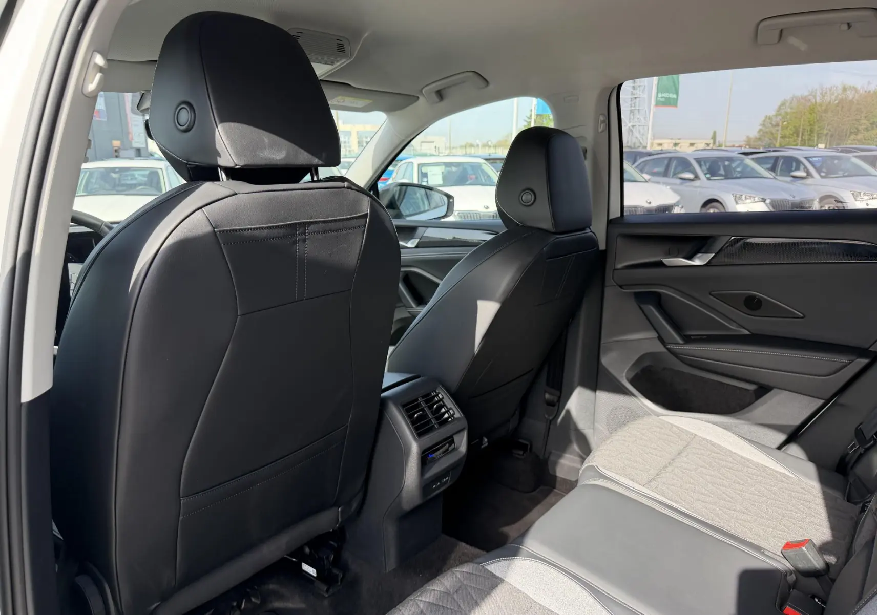Vue intérieure arrière droite du Volkswagen Tiguan blanc 2025, sièges avant cuir noir et banquette tissu gris.