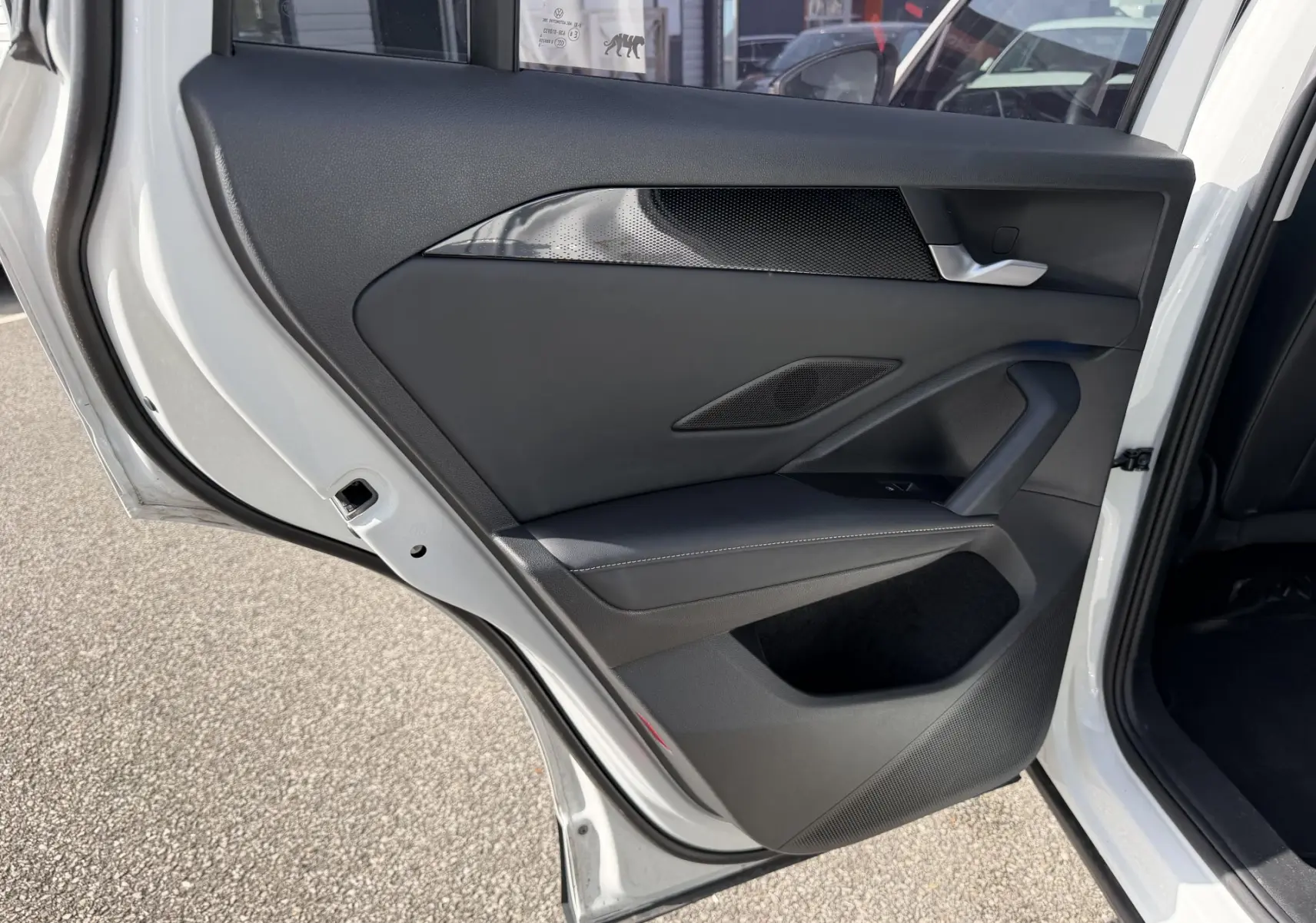 Vue intérieure de la porte arrière gauche blanche du Volkswagen Tiguan 2025 avec garniture noire et insert décoratif.