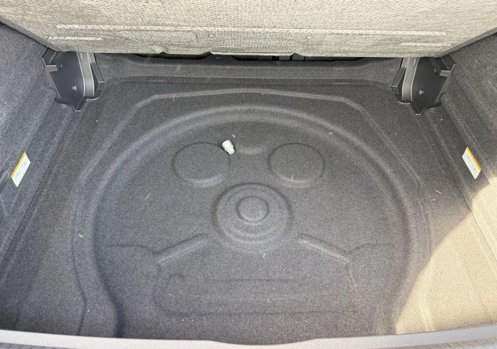 Coffre ouvert vu de dessus du Volkswagen Tiguan blanc, montrant l’espace de rangement vide et moquette grise.