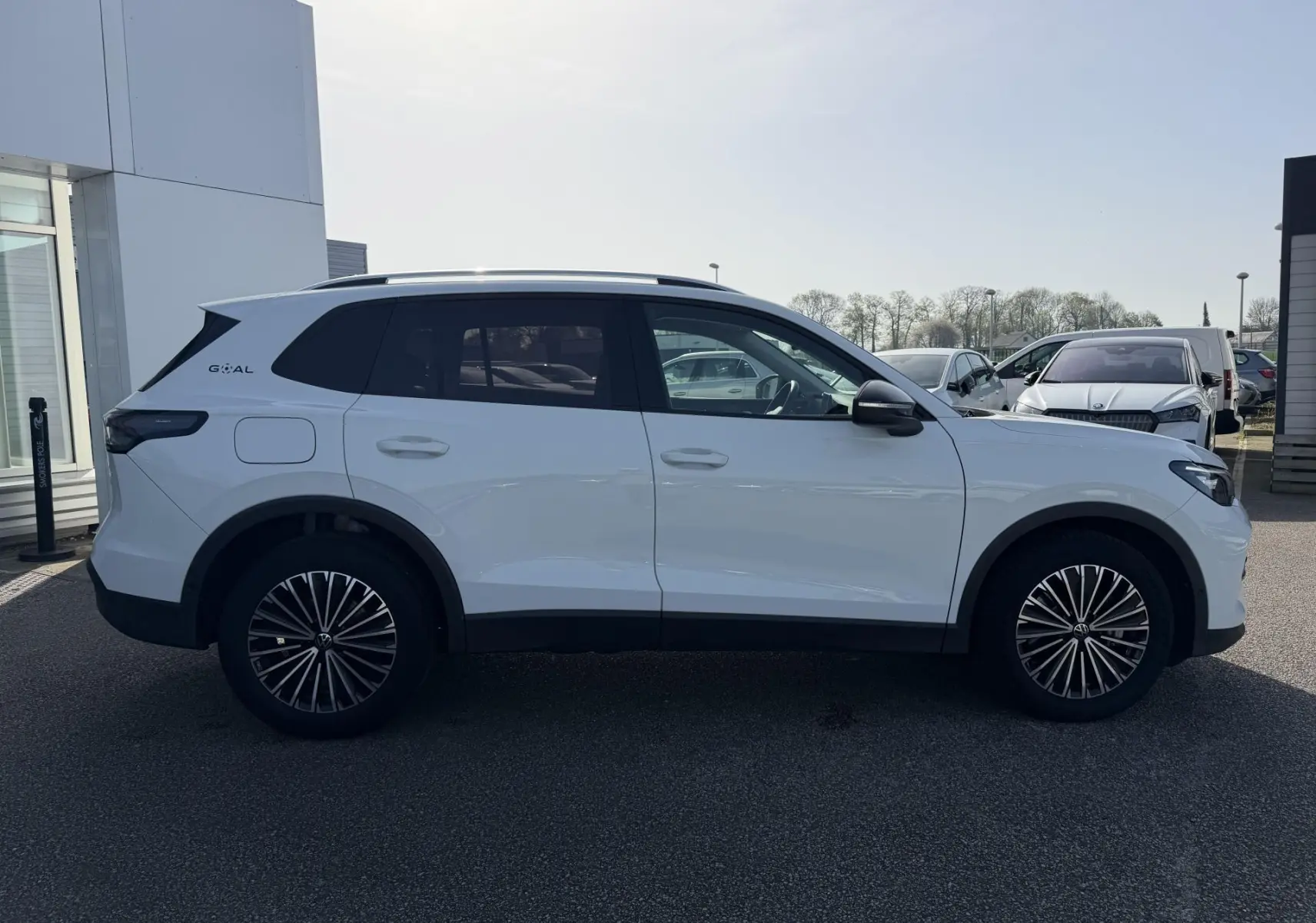 Volkswagen Tiguan blanc vu de profil côté gauche, avec jantes alliage noir et surface tournée brillante.