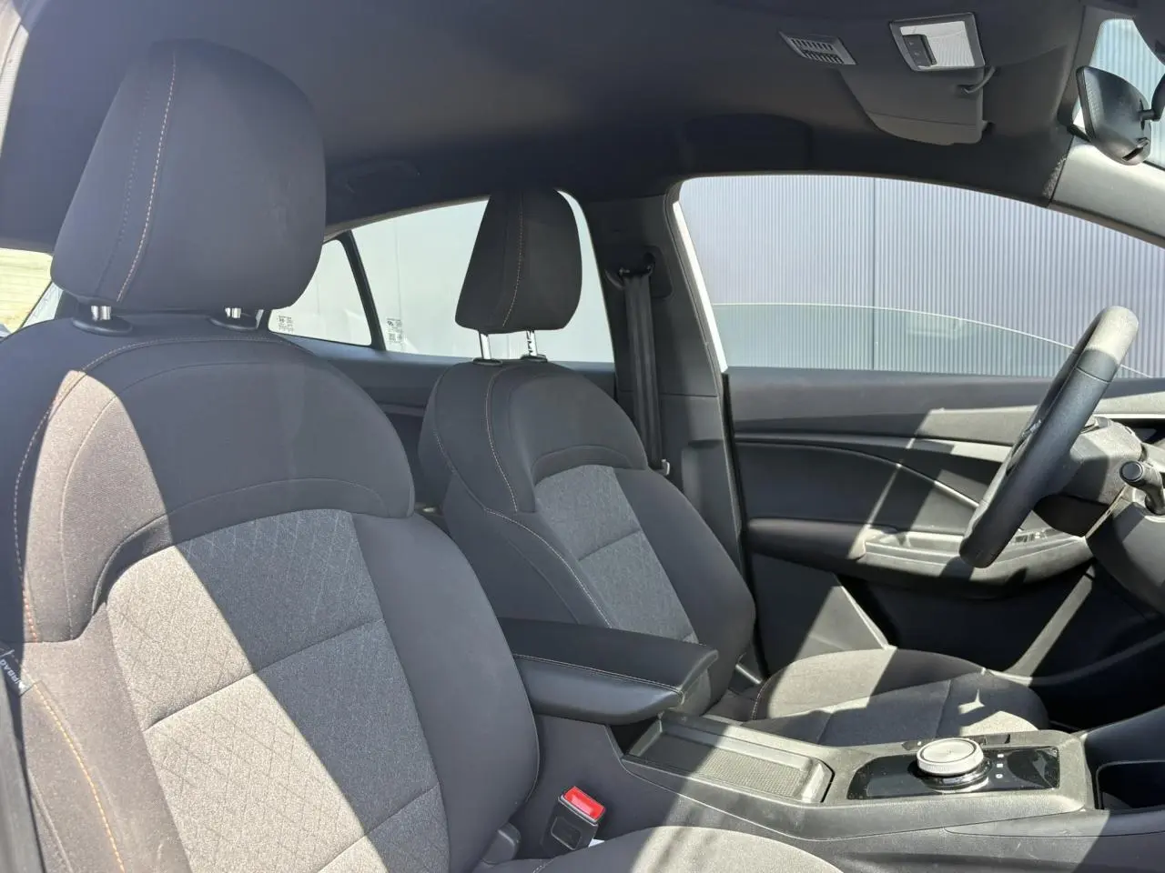 Vue intérieure côté droit des sièges tissu noir avec accoudoir central et volant du MG3 1.5 Hybrid+ 2025.