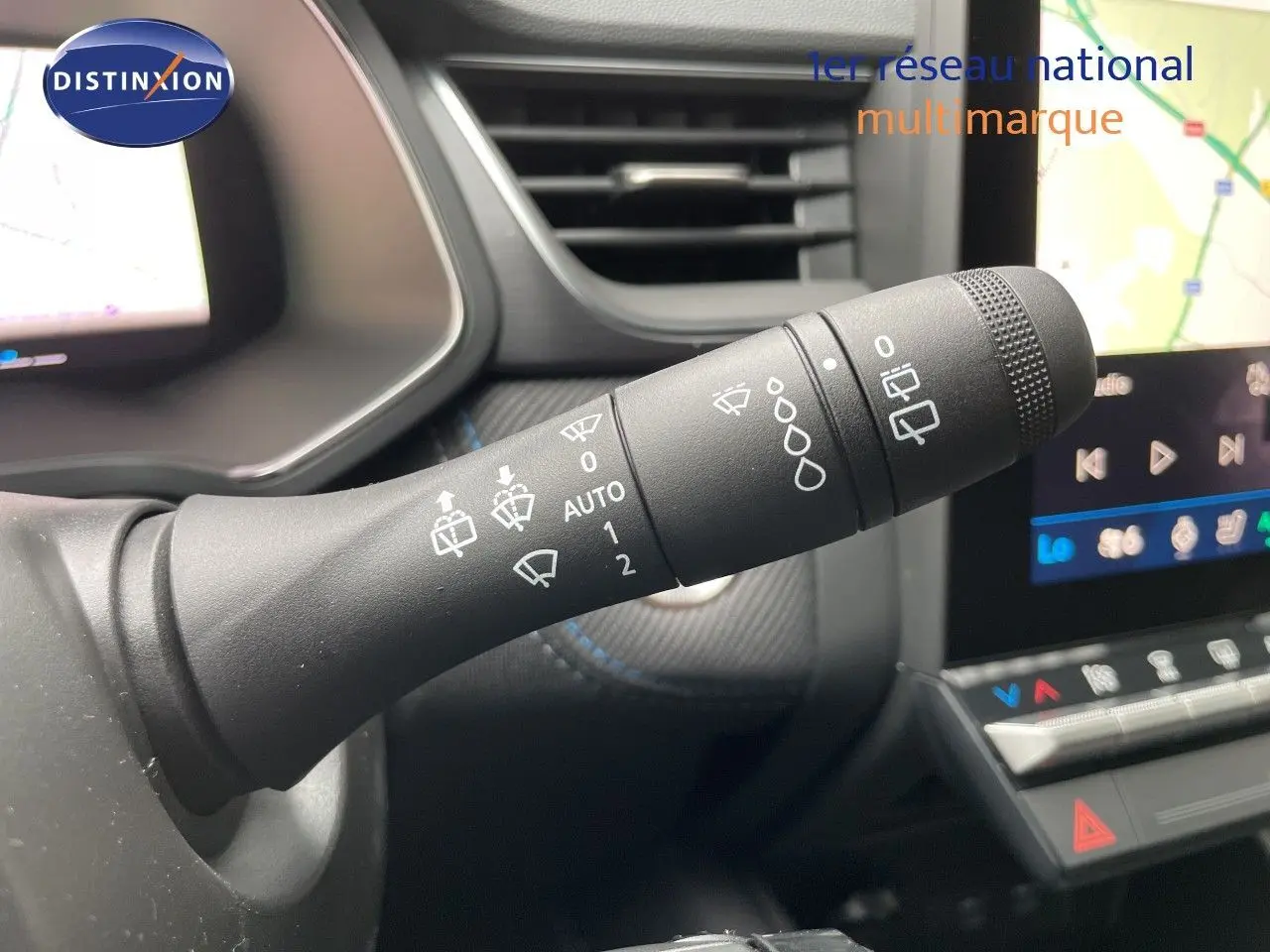 Gros plan sur la commande des essuie-glaces dans l’habitacle gris du Renault Symbioz 2026 avec écran tactile en arrière-plan.