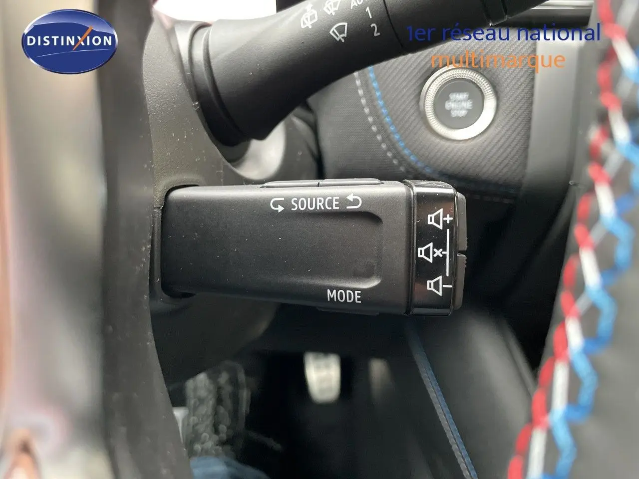 Gros plan sur la commande au volant du Renault Symbioz gris Rafale, avec bouton source et mode, volant cuir noir.