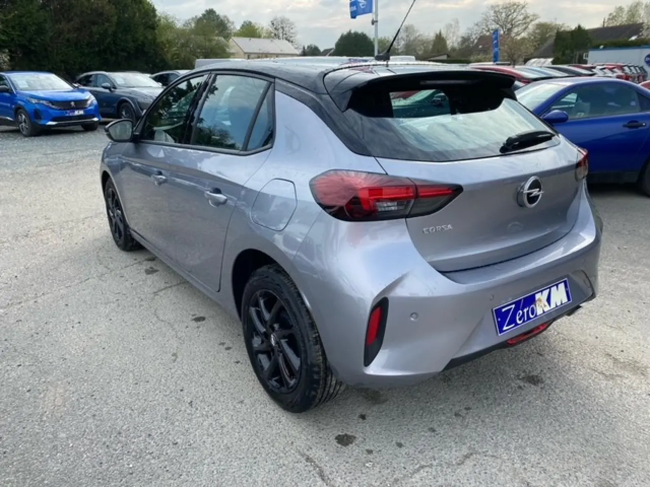 Opel Corsa gris magnetic vue 3/4 arrière droit avec toit noir et jantes alliage noires brillantes.