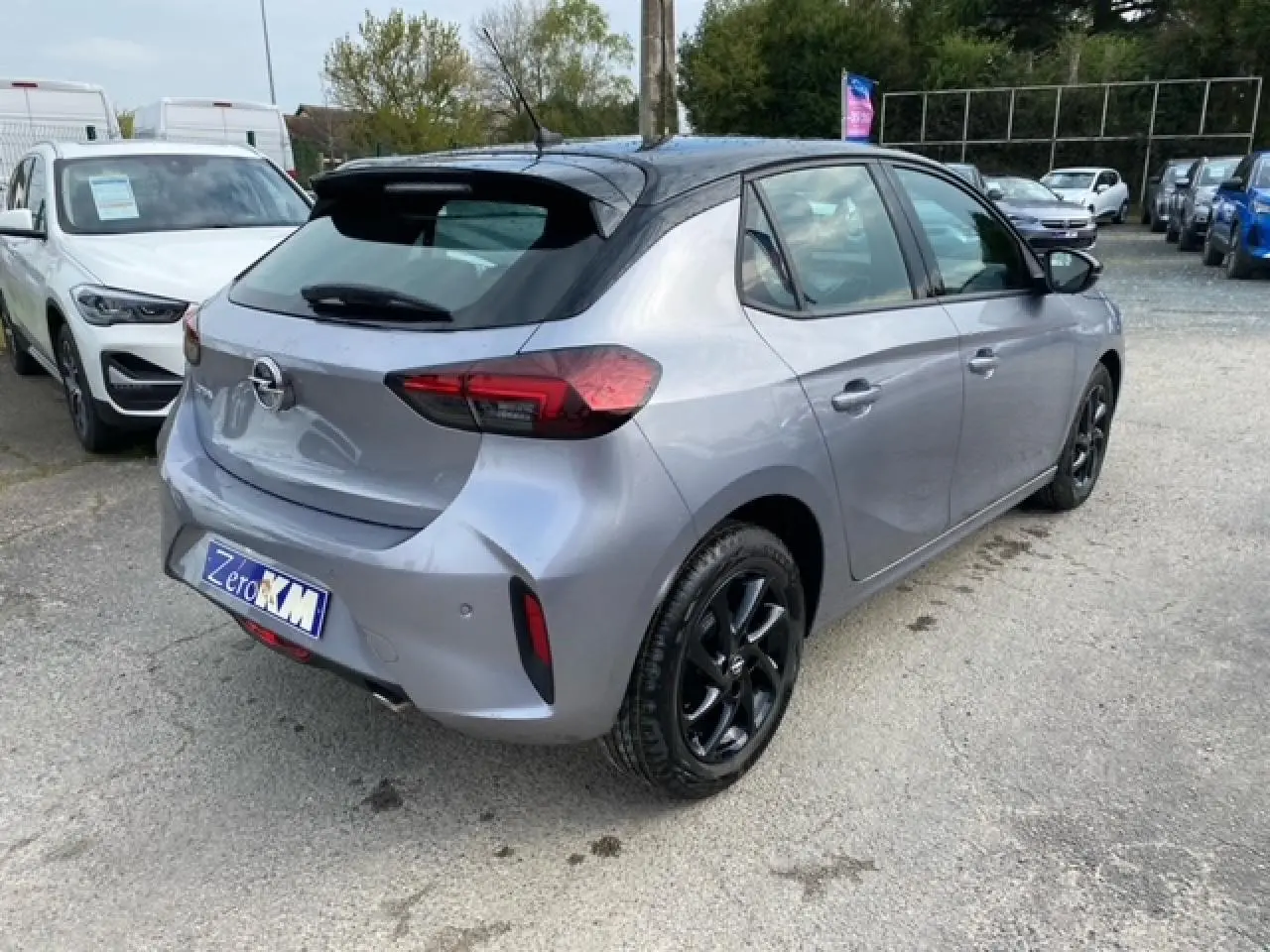 Opel Corsa gris magnetic vue 3/4 arrière droit avec toit noir et jantes alliage noires brillantes.