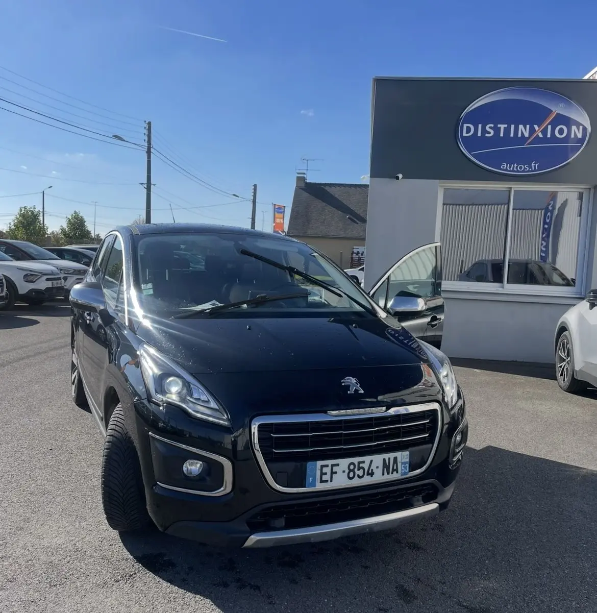 Peugeot 3008 noir vue 3/4 avant droit, phares bi-Xénon allumés, porte avant droite ouverte, stationnée devant un bâtiment.