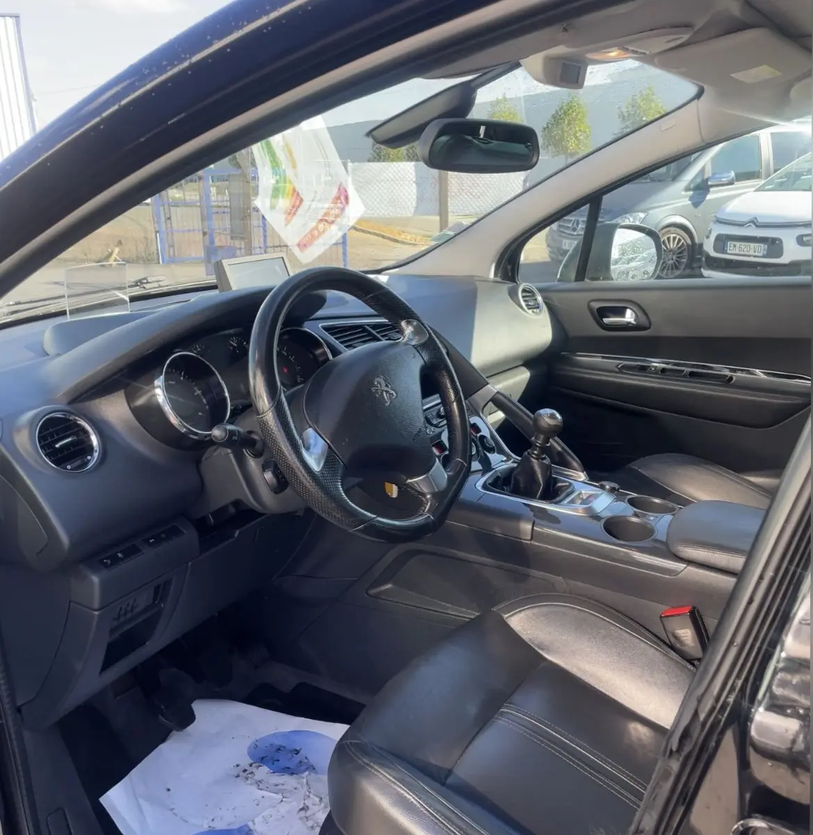 Intérieur noir du Peugeot 3008 2016 vu côté conducteur, volant cuir, levier de vitesses manuel et sièges en cuir.