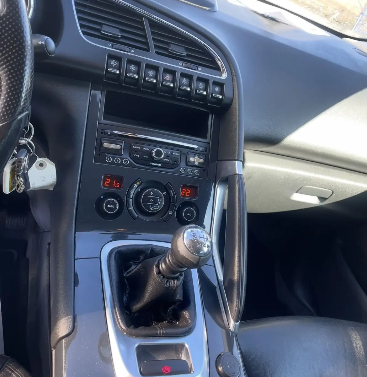 Intérieur de Peugeot 3008 noir, vue rapprochée sur la console centrale avec levier de vitesse manuel et commandes climatisation.