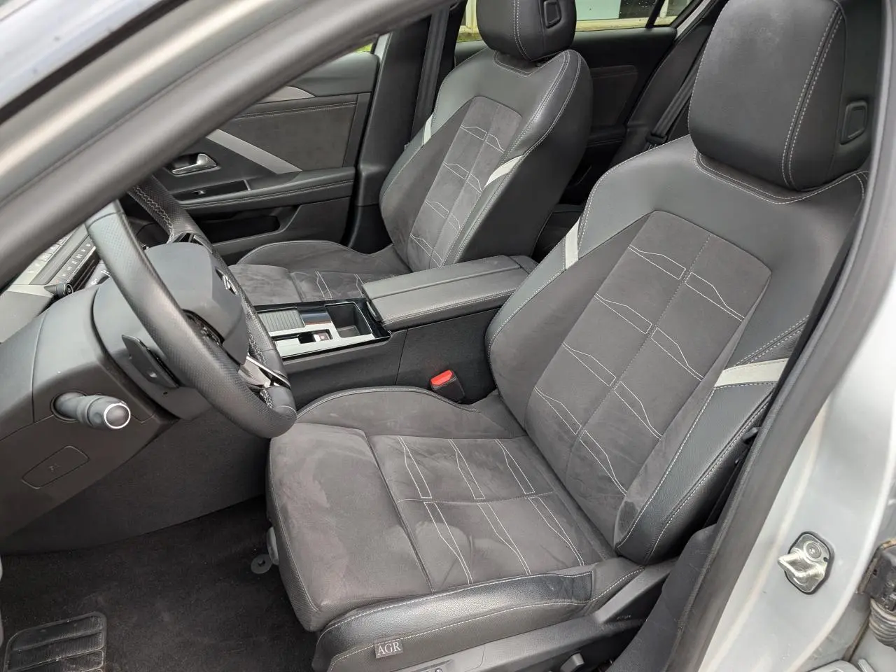 Vue intérieure côté conducteur de l'Opel Astra 2024 avec sièges mixte Alcantara et cuir gris foncé et console centrale noire.