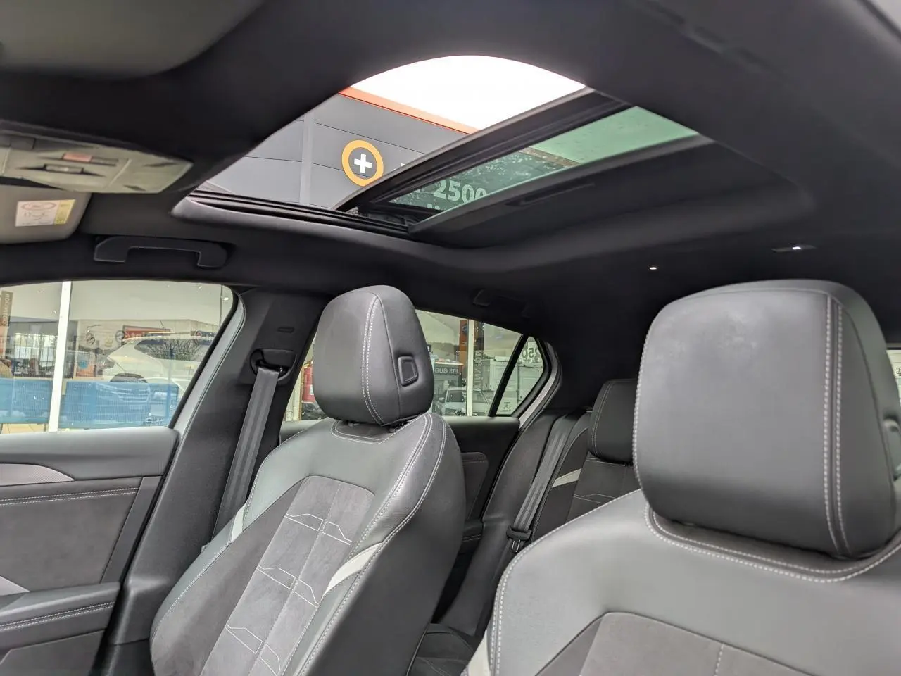 Vue intérieure montrant les sièges avant en sellerie mixte gris et toit ouvrant panoramique de l'Opel Astra 2024.