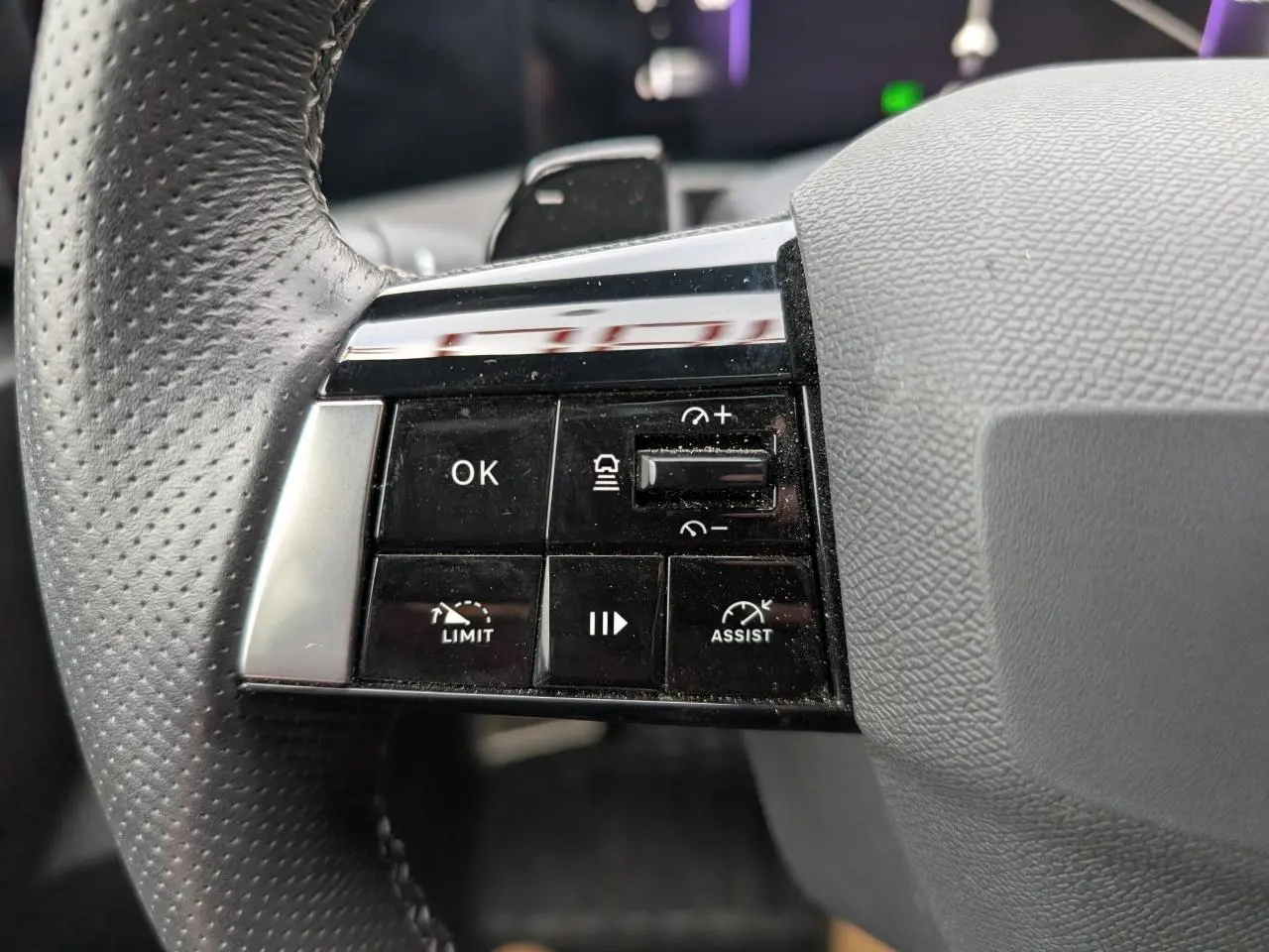 Gros plan sur les commandes à gauche du volant cuir perforé de l'Opel Astra 2024 gris métallisé.