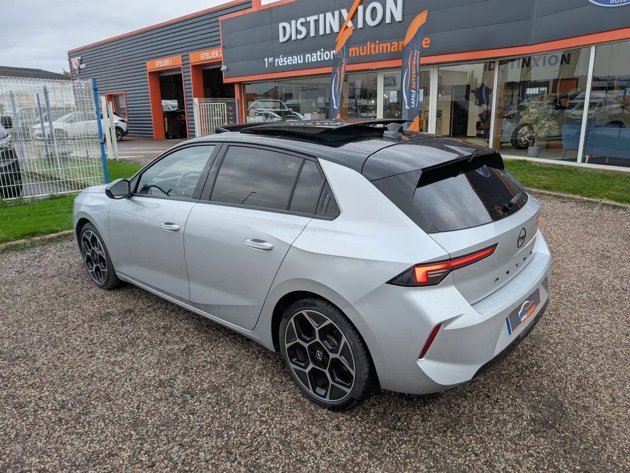 Opel Astra 2024 gris métallisé vue 3/4 arrière droit avec toit noir et jantes alliage diamantées.