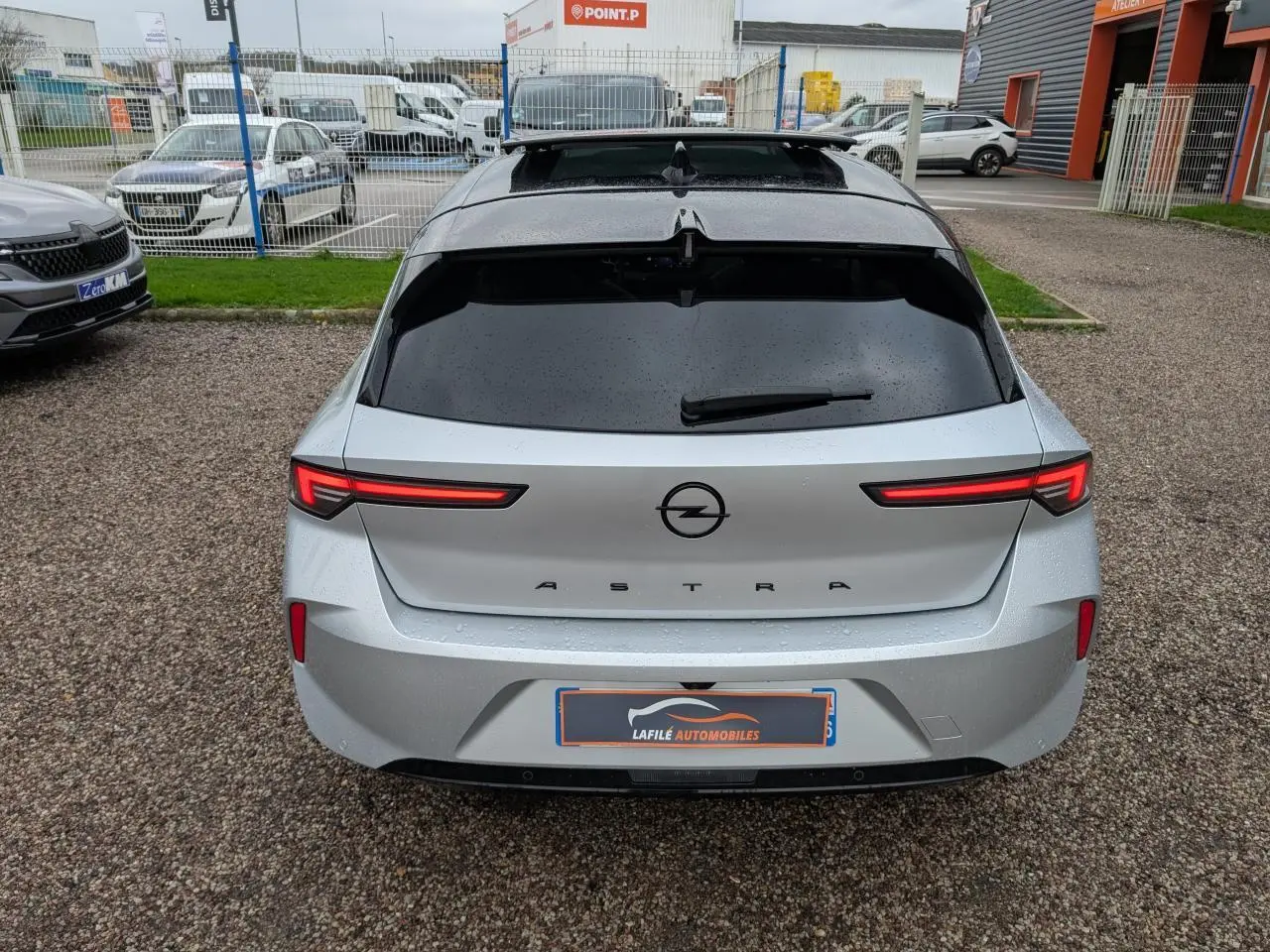Vue arrière d'une Opel Astra gris métallisé avec feux LED fins et vitres arrière surteintées.