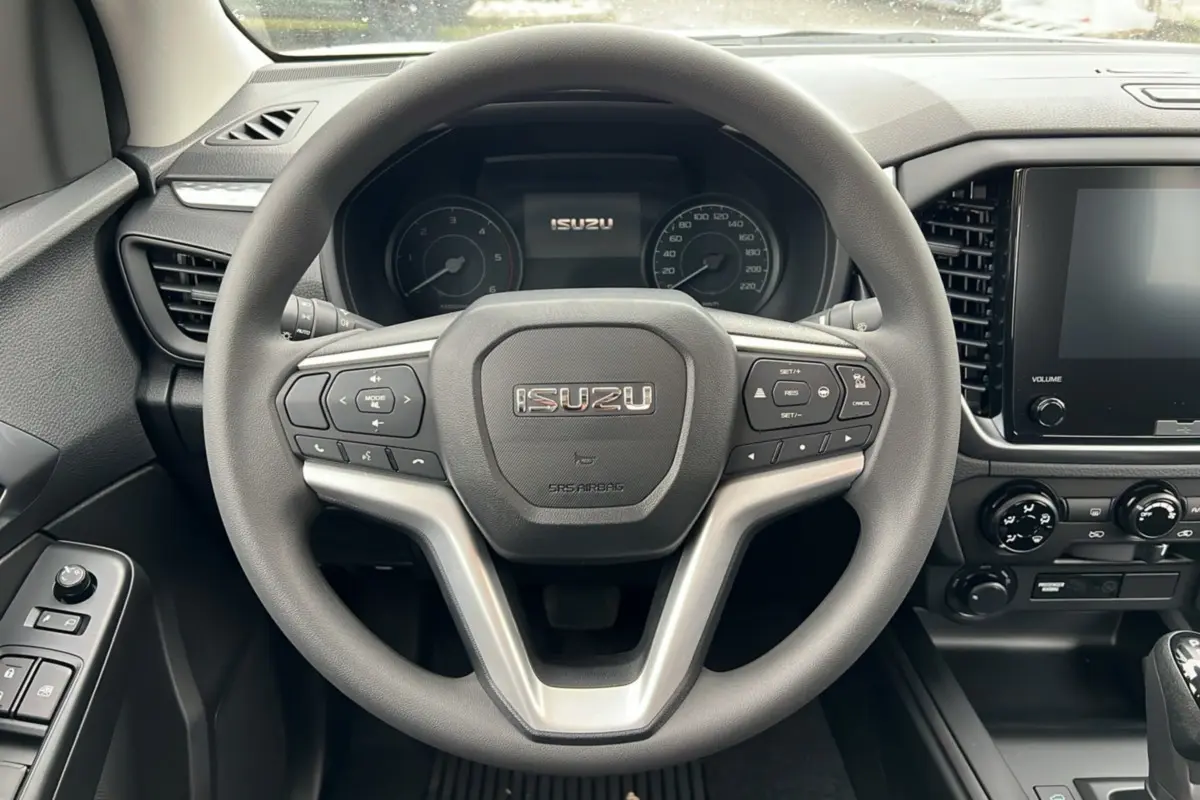 Vue intérieure centrée sur le volant multifonctions d’un Isuzu D-MAX 2026 avec tableau de bord et écran tactile.