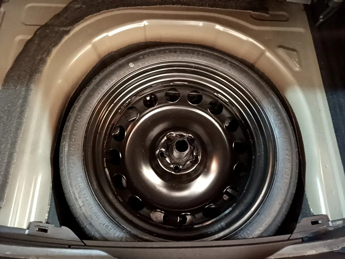 Vue plongeante sur la roue de secours noire en acier dans le coffre du Volkswagen Taigo 1.5 TSI 150 DSG R-Line 2023.