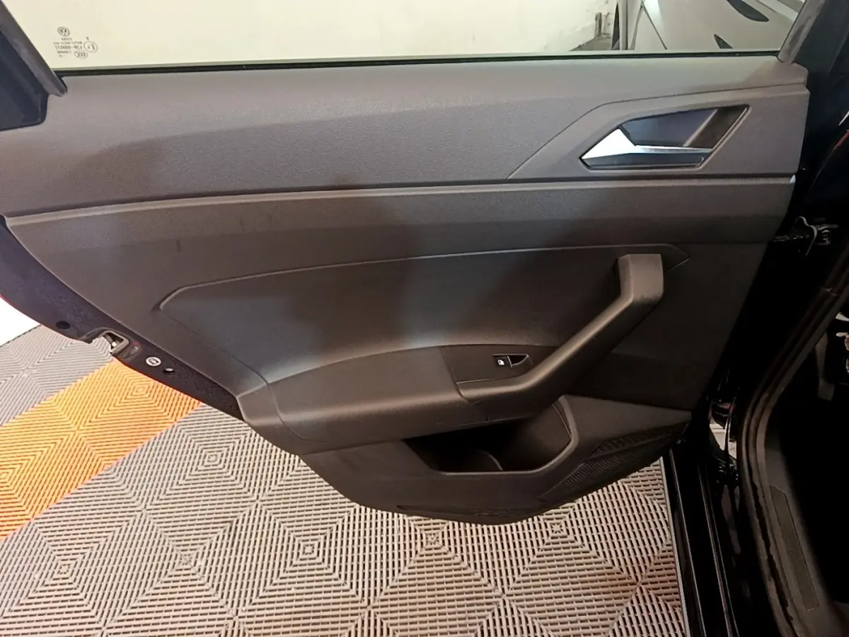 Vue intérieure du panneau de porte côté gauche noir du Volkswagen Taigo 1.5 TSI 150 DSG R-Line 2023 avec poignée intégrée.