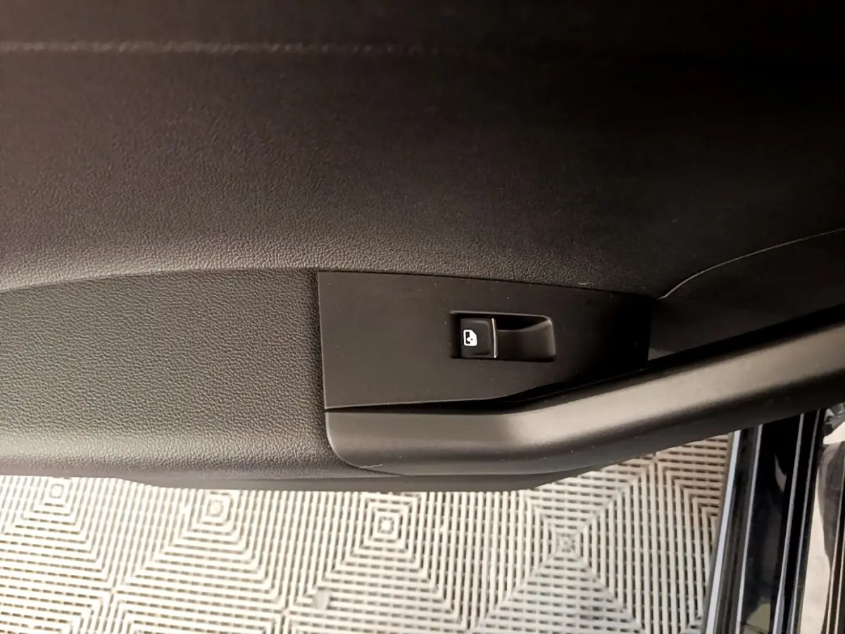Détail de la commande de verrouillage sur la portière intérieure noire d’un Volkswagen Taigo 1.5 TSI 150 DSG R-Line 2023.