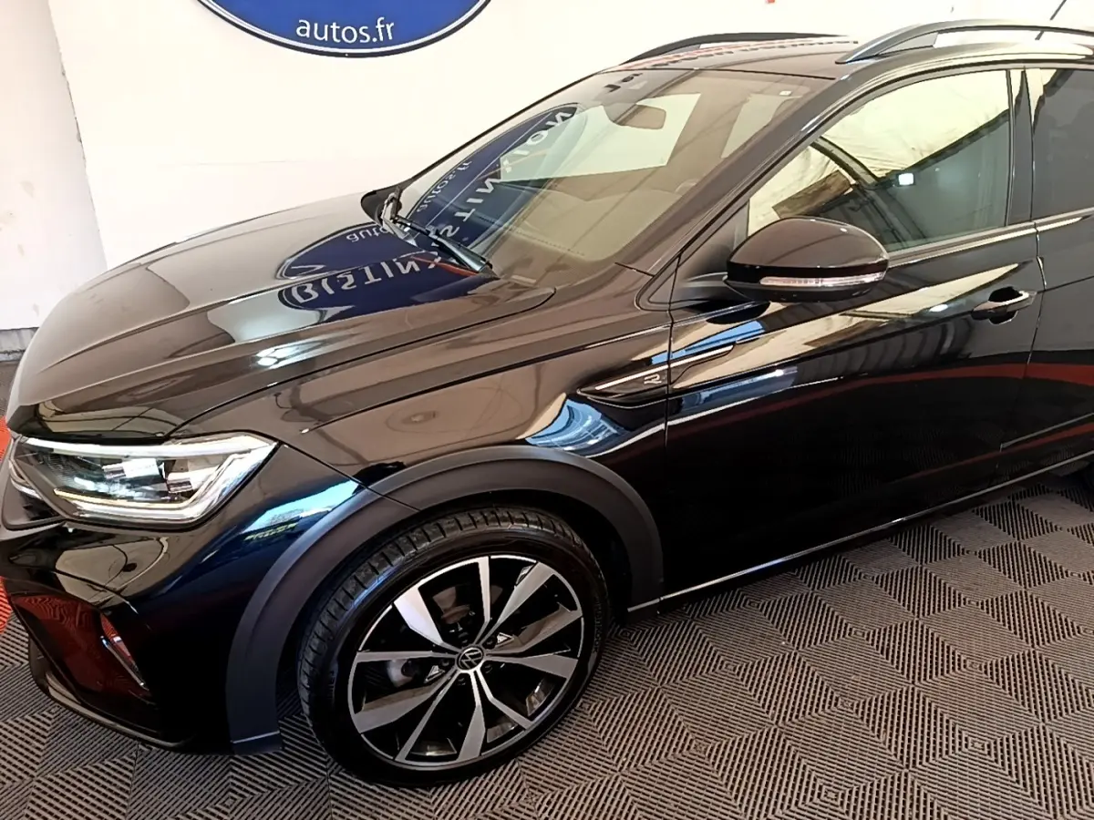 Vue de profil avant droit du Volkswagen Taigo noir 1.5 TSI R-Line avec jantes alliage et rétroviseur noir brillant.