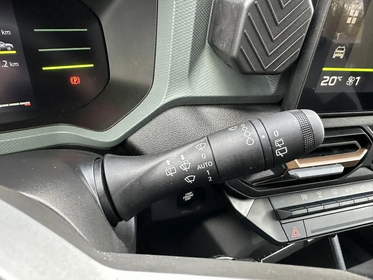 Vue rapprochée du commodo d’essuie-glace noir dans l’habitacle du Dacia Duster blanc Glacier 2025.