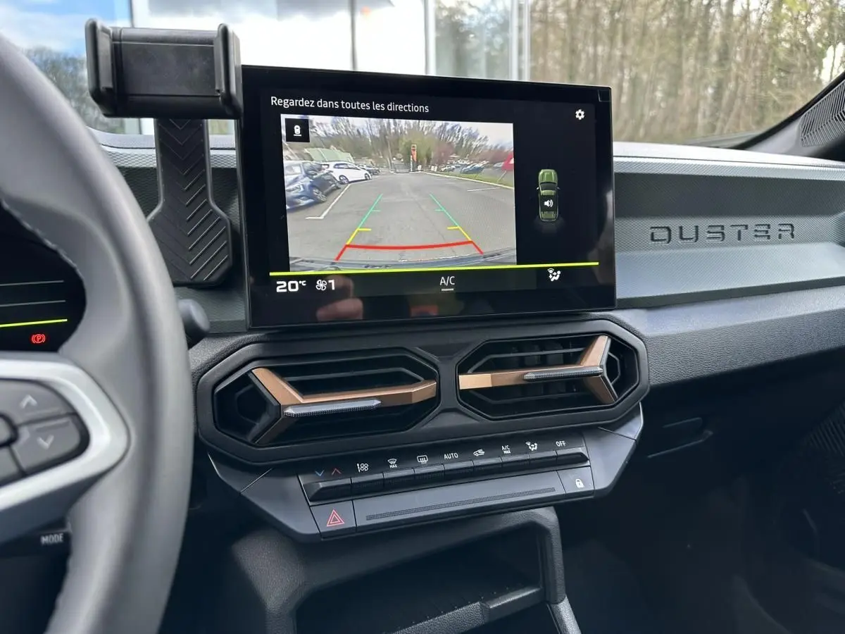 Vue intérieure du tableau de bord du Dacia Duster 2025 avec écran tactile et aérateurs hexagonaux cuivrés.