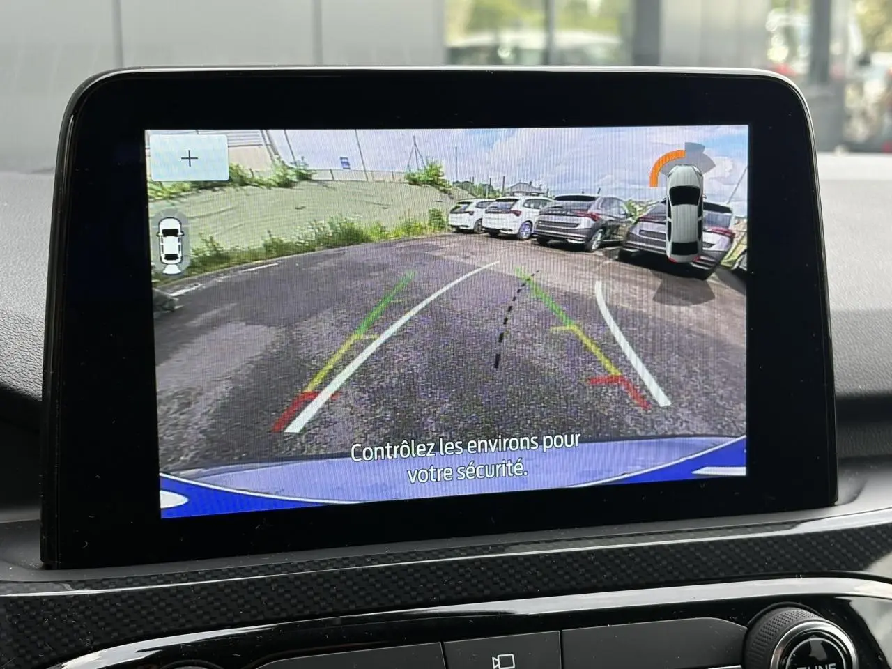 Écran tactile intérieur montrant la caméra de recul du Ford Kuga bleu azur, avec lignes d’aide au stationnement.