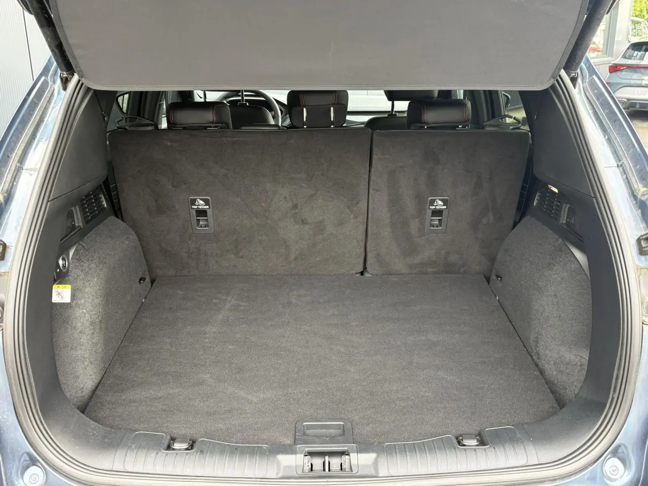 Coffre ouvert vu de l'arrière d'un Ford Kuga bleu azur 2023, banquette arrière en position verticale.