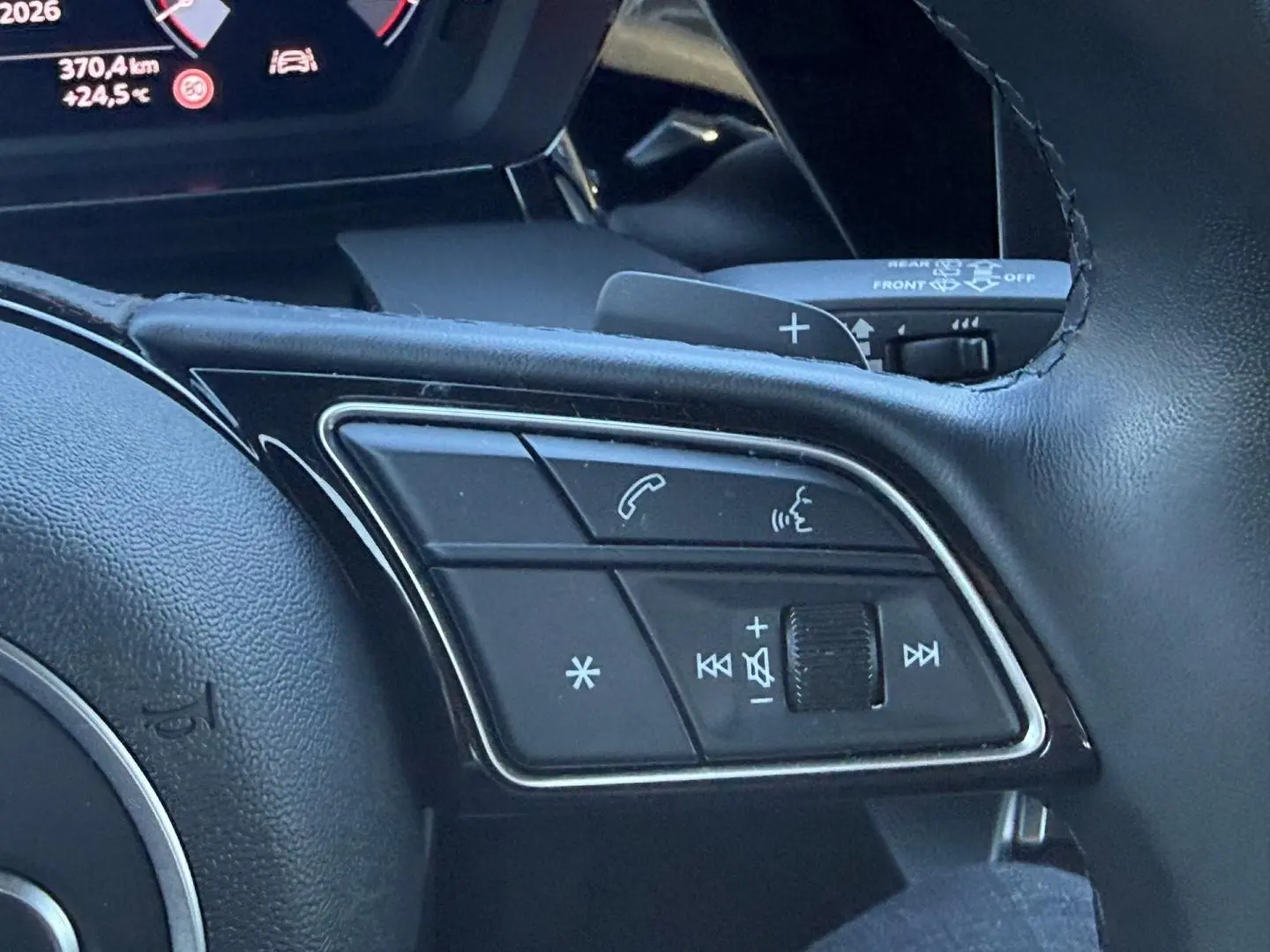 Gros plan sur les commandes vocales et audio au volant cuir noir de l'Audi A3 Sportback 2024.