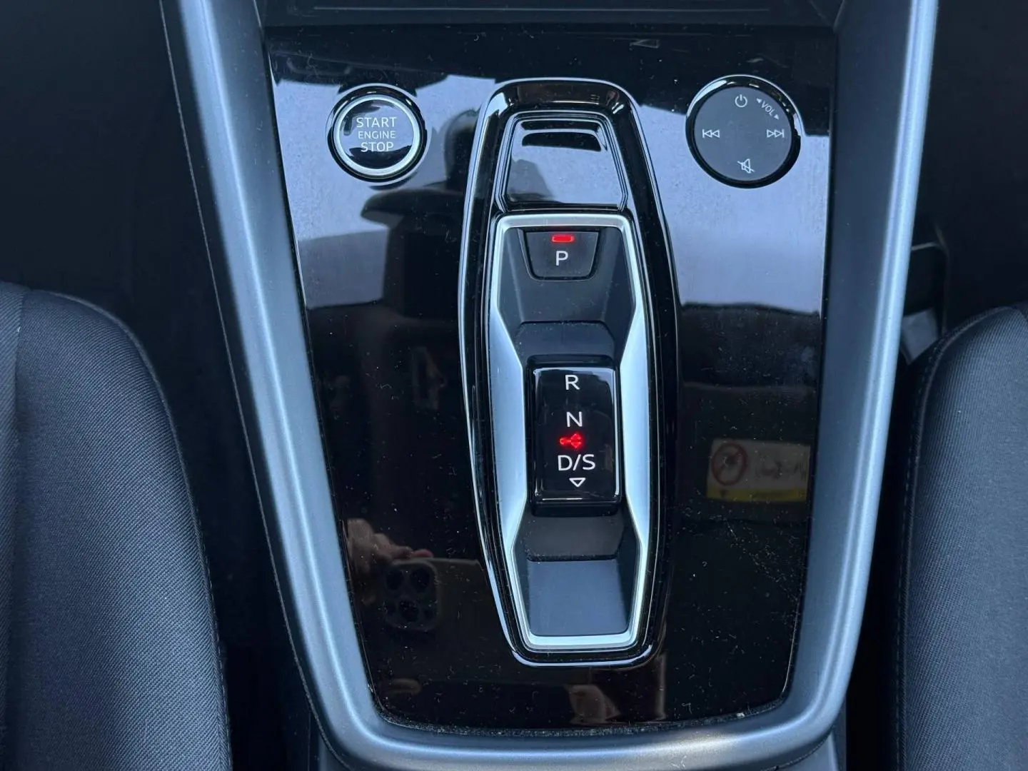 Gros plan sur la console centrale noire brillante avec sélecteur de boîte auto et bouton Start/Stop de l'Audi A3 Sportback 2024.