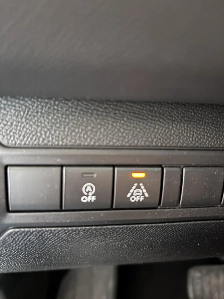Gros plan sur les boutons de désactivation de l'arrêt auto et de l'alerte de franchissement de ligne dans une Peugeot 308 gris foncé de 2019.