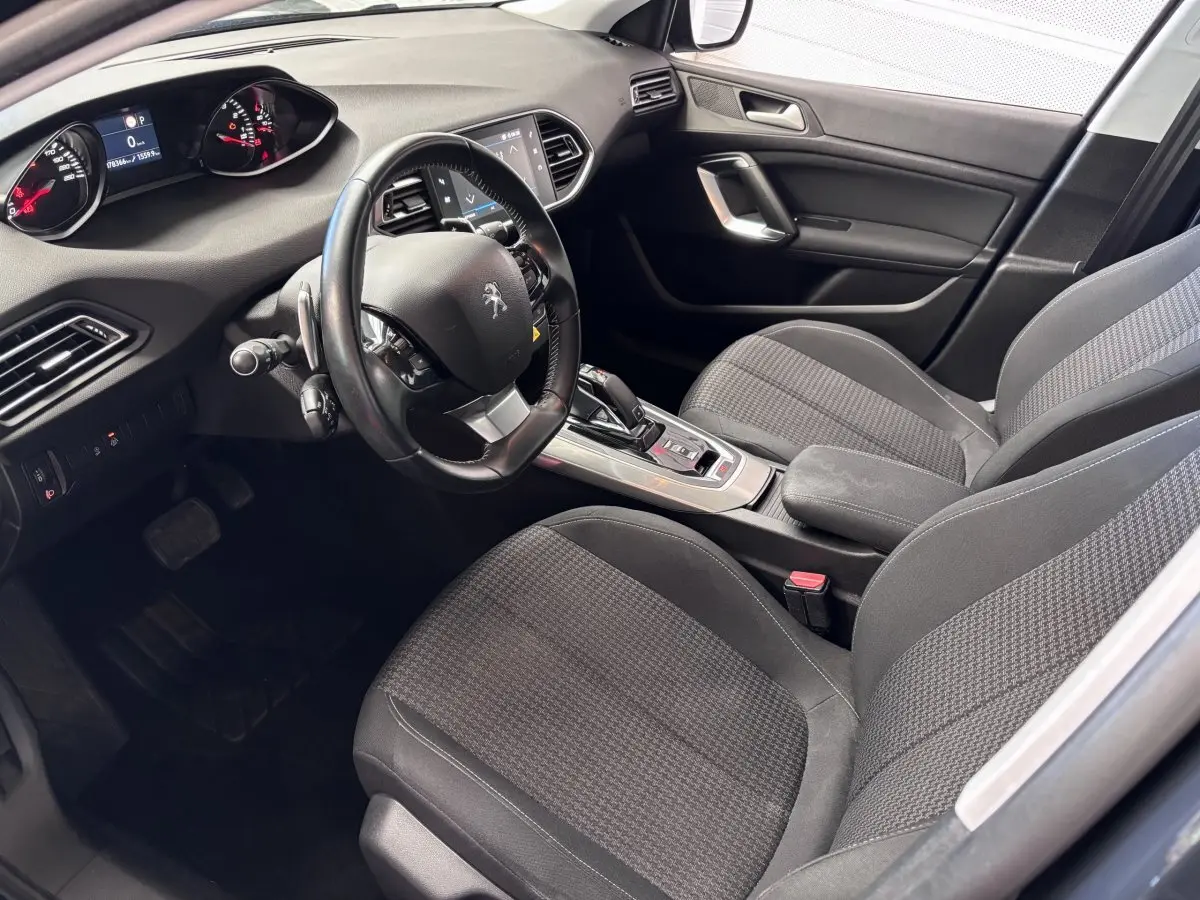 Intérieur avant droit de la Peugeot 308 gris foncé, volant multifonction et console centrale avec boîte automatique visible.