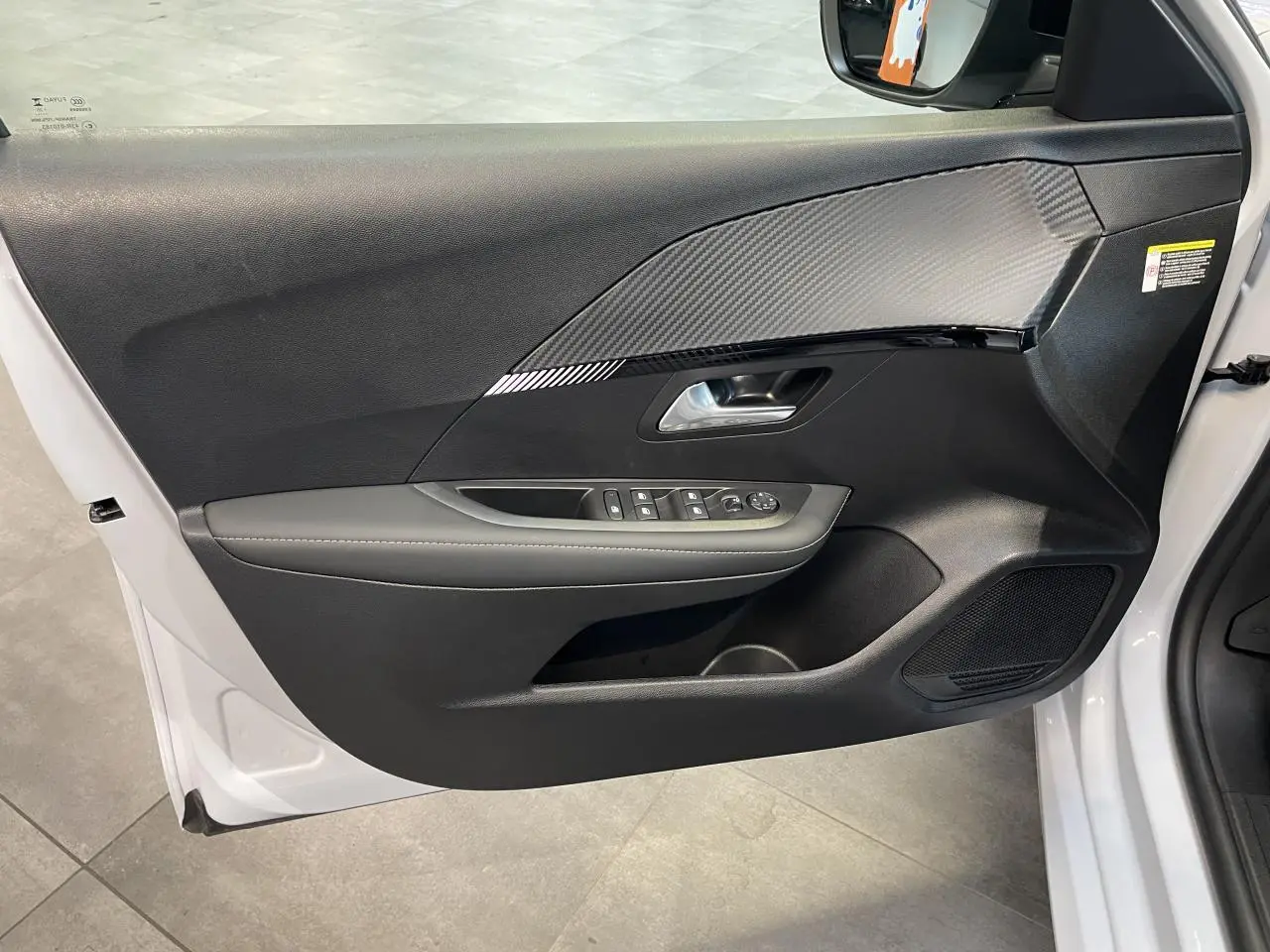 Vue intérieure côté gauche de la porte avant blanche okenite de la Peugeot 208 avec habillage noir et insert effet carbone.