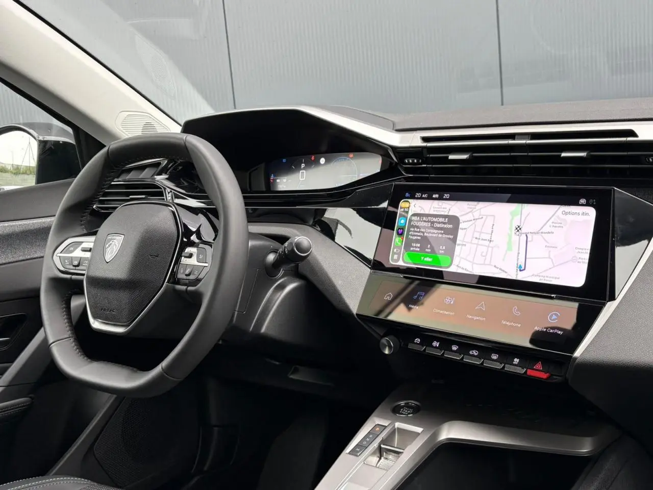 Vue intérieure côté conducteur du tableau de bord noir et écran tactile affichant la navigation du Peugeot 308 SW Hybrid 2025.