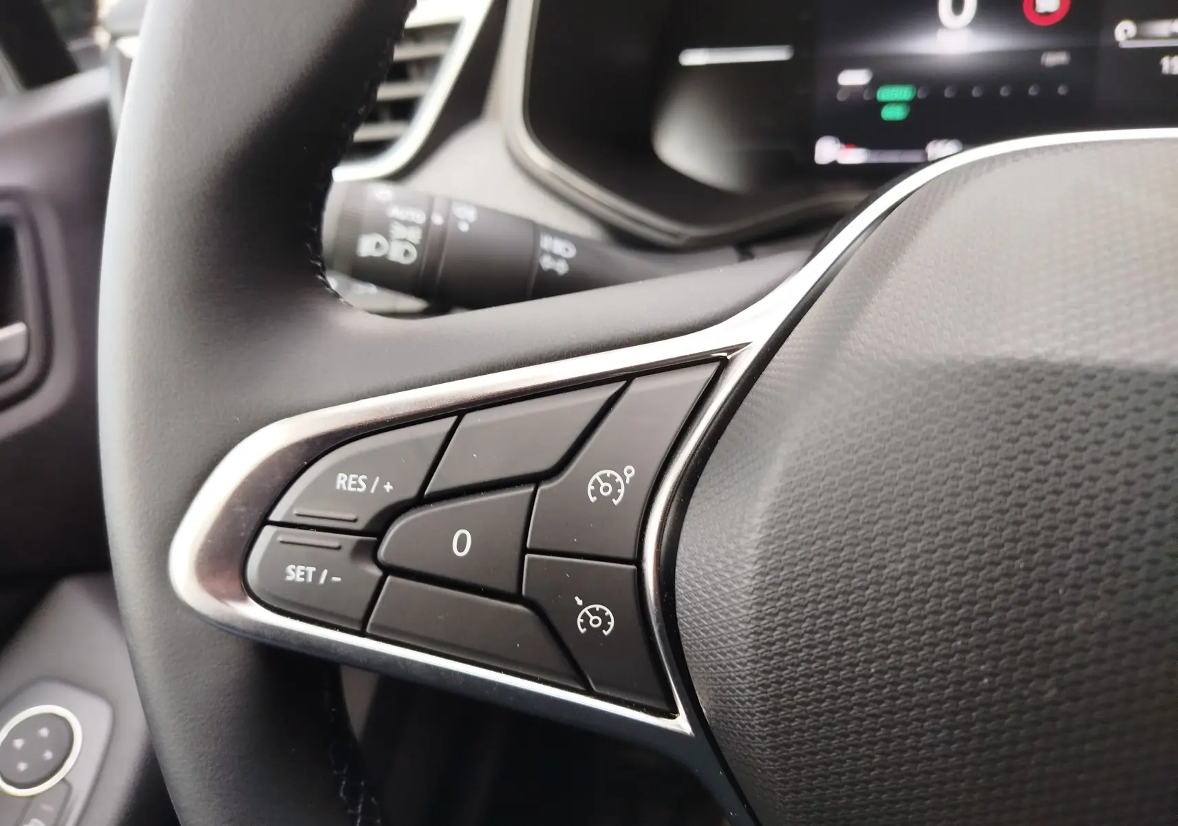 Gros plan sur les commandes de régulateur de vitesse au volant noir de la Renault Clio TCE 90CH X-TRONIC Evolution rouge flamme.