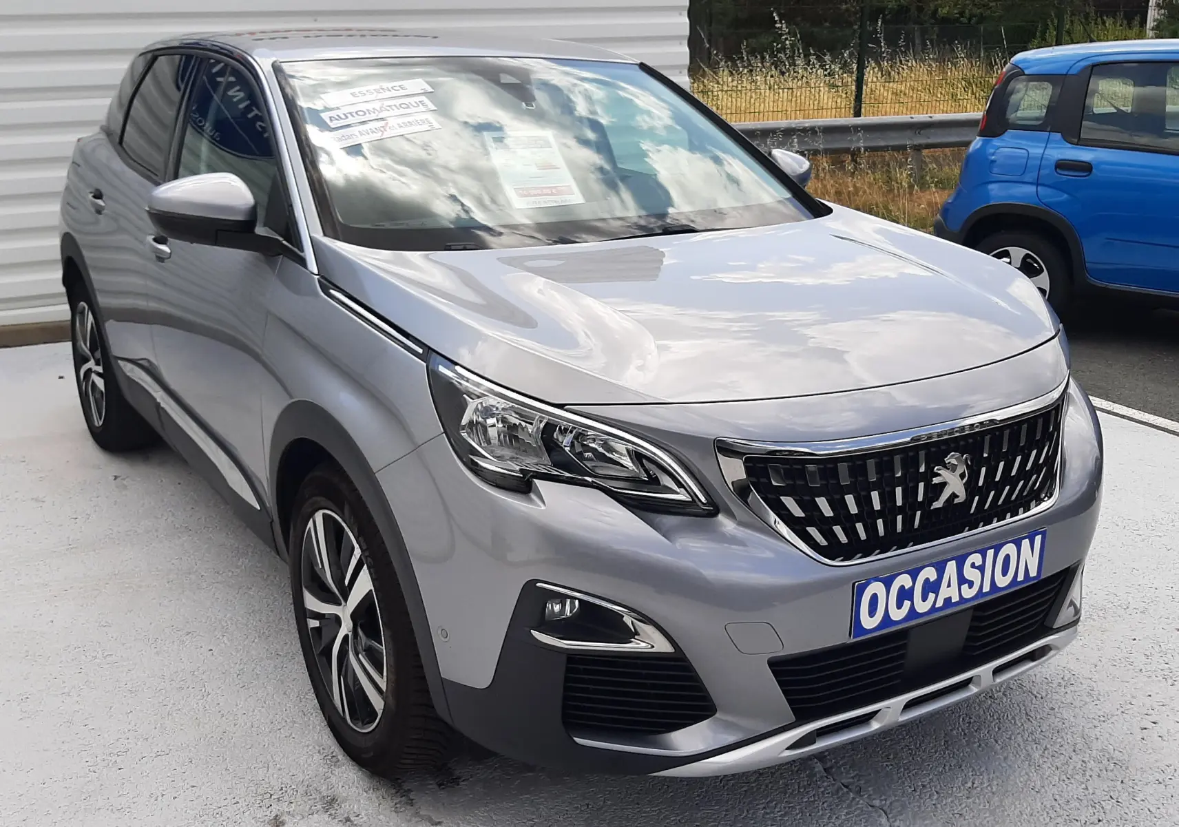 Peugeot 3008 gris vue 3/4 avant droit, avec calandre noire et plaque "OCCASION" visible sur un parking.