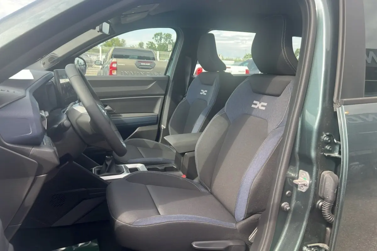 Vue intérieure côté conducteur du Dacia Bigster 2025 vert cèdre, mettant en valeur les sièges tissu avec logo DC brodé.