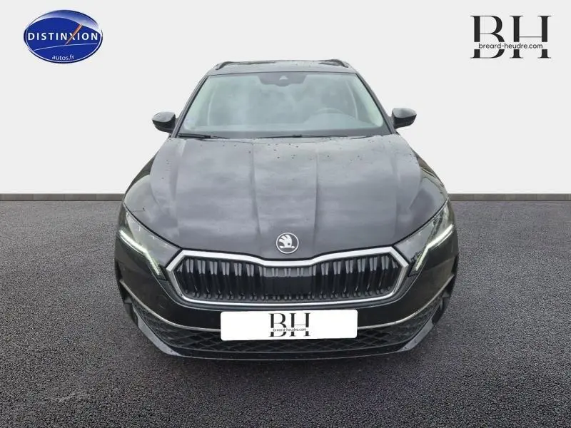 Vue frontale d'une Skoda Octavia Combi noire Magic nacré avec calandre chromée et phares LED allumés.
