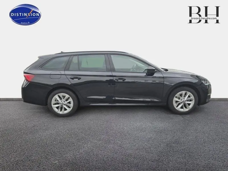 Profil latéral droit d'une Skoda Octavia Combi noire nacrée 2024 avec jantes alliage argentées et vitres arrière surteintées.