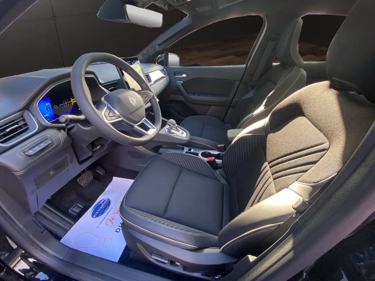 Intérieur avant droit de la Renault Symbioz Iconic E-Tech Hybrid 2025 avec sièges noirs et tableau de bord digital.