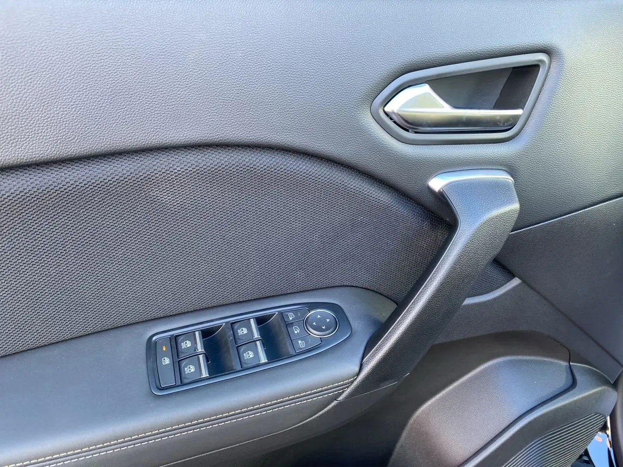 Détail de la porte côté gauche de la Renault Symbioz Iconic E-Tech Hybrid noire, avec commandes des vitres et poignée argentée.