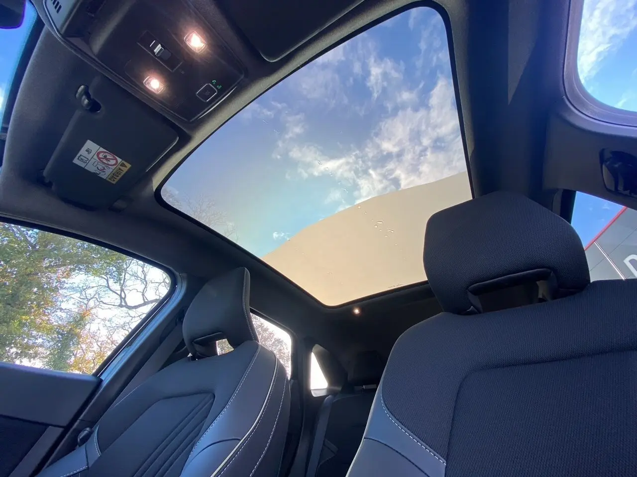 Vue intérieure avant du Renault SYMBIOZ noir étoile, mettant en valeur le toit panoramique Solarbay et les sièges avant en tissu.